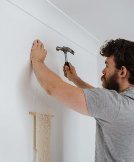 man hammering a decor on the white wall