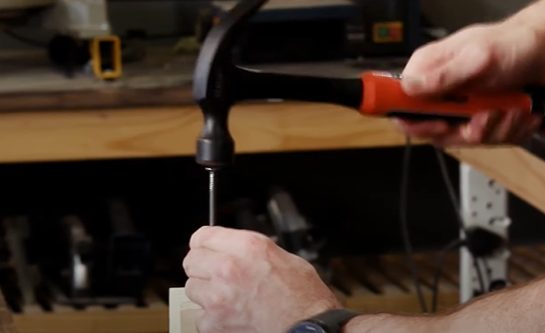 man tapping the head of a screw with a hammer