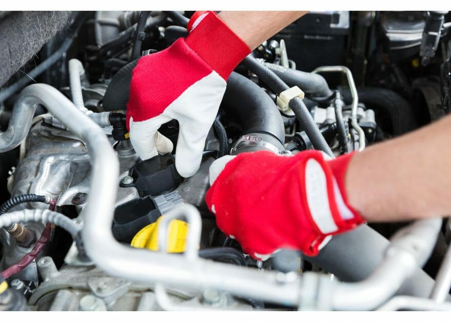 mechanic in red/white gloves checking car engine