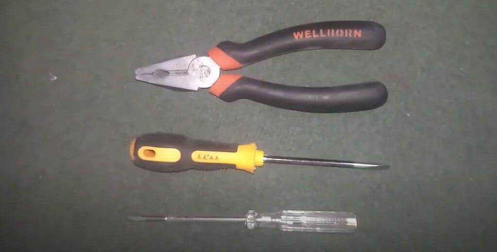 A plier, and screwdrivers on a black table