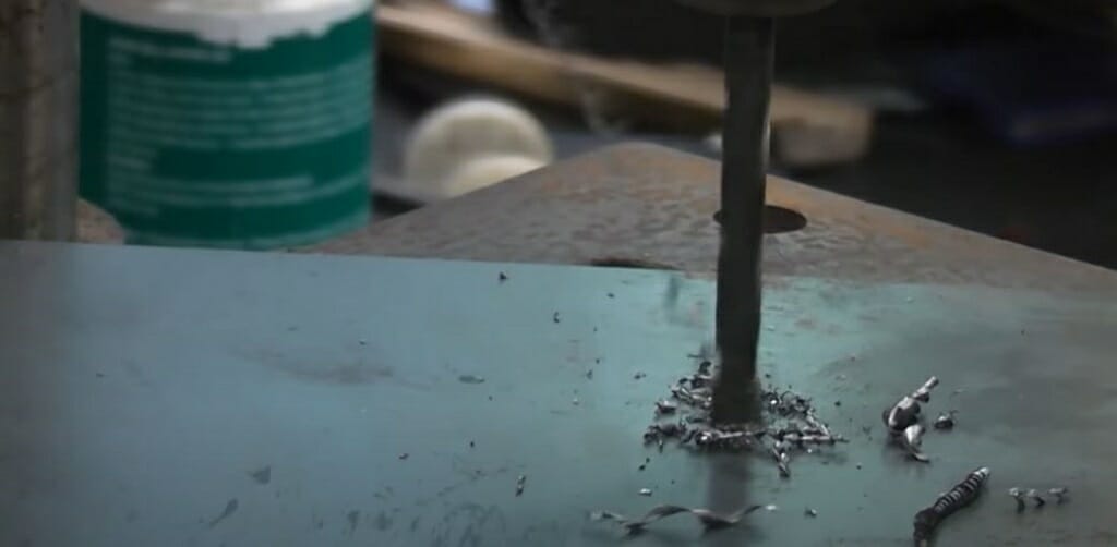 A person testing the drill bit on the steel table