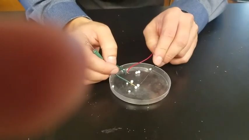 hand holding red and green wires to test calcium chloride