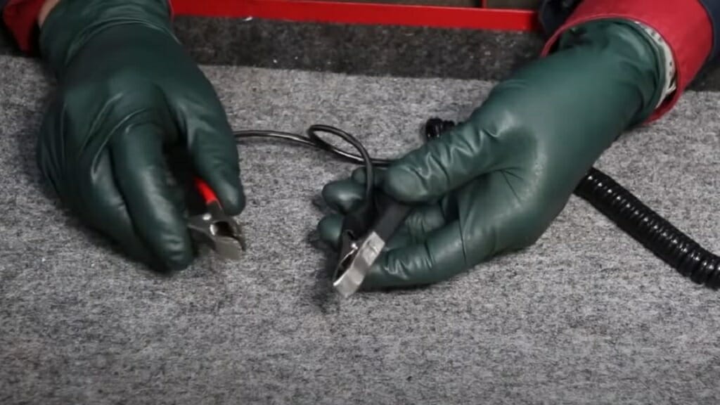 hands with safety gloves holding alligator clips