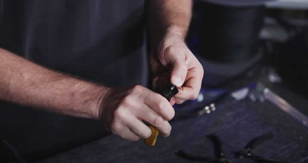 man stripping a wire with tool stripper