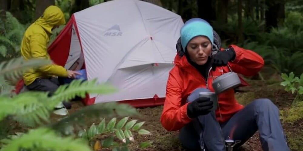 a woman at a camping site pouring a coffee