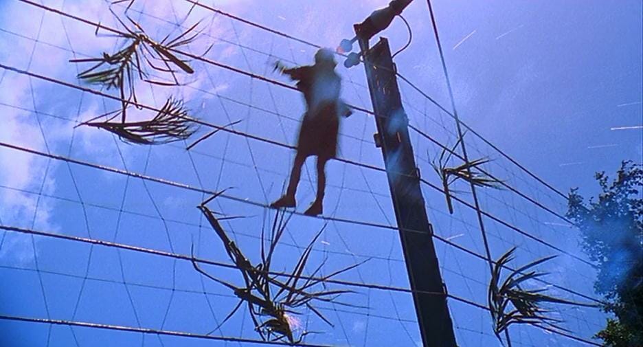 An electrician climbing on a big electric fence