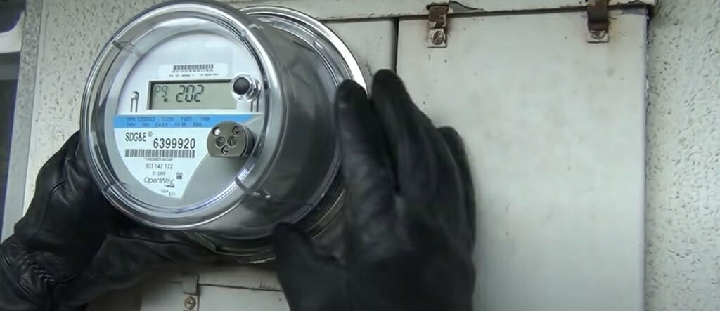 hand with black gloves touching the electric meter