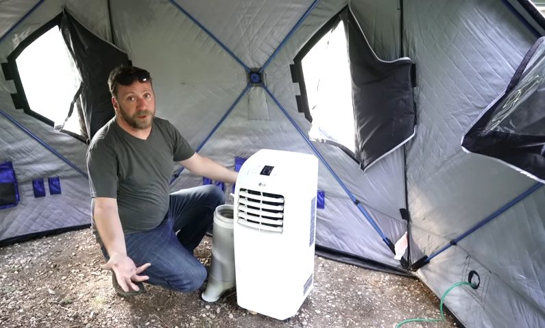 man besides an AC inside a tent