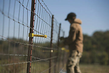 A man checking on an electric fence