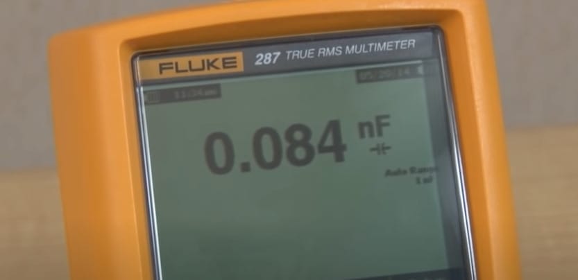 A fluke multimeter is shown with 0.084 nF reading on its screen