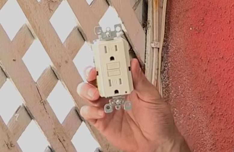 hand holding a GFCI outlet