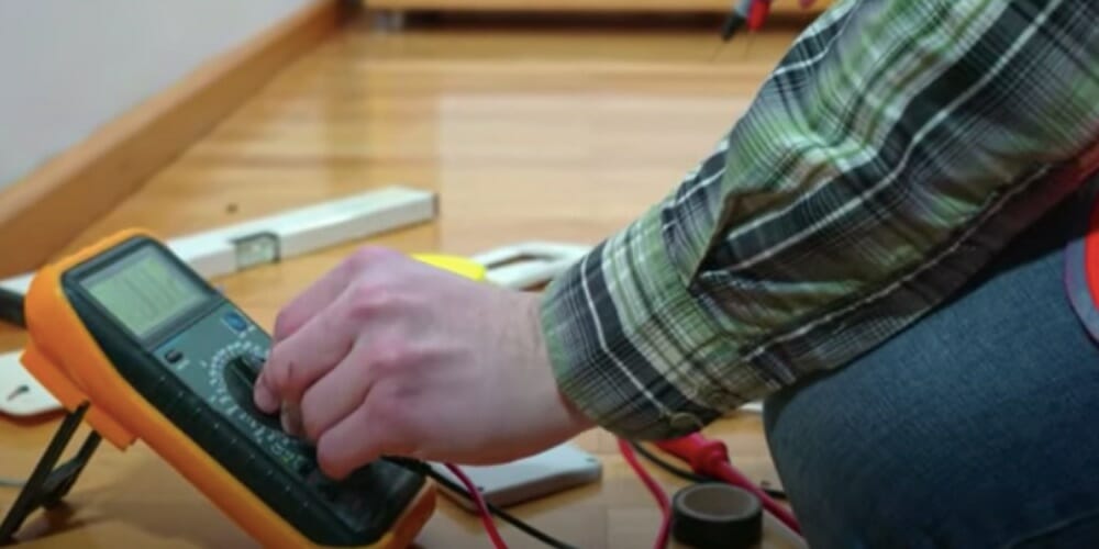 man checking ground wire with multimeter