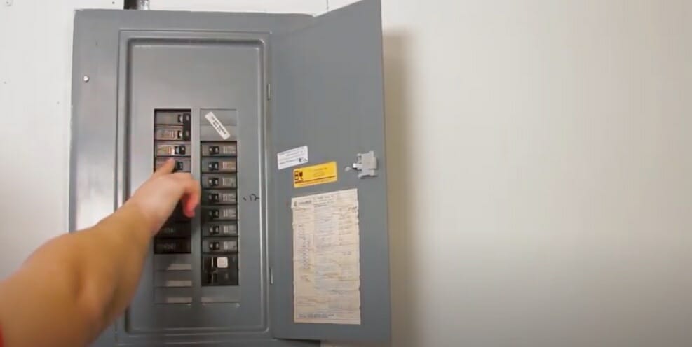 man's hand on a circuit breaker panel