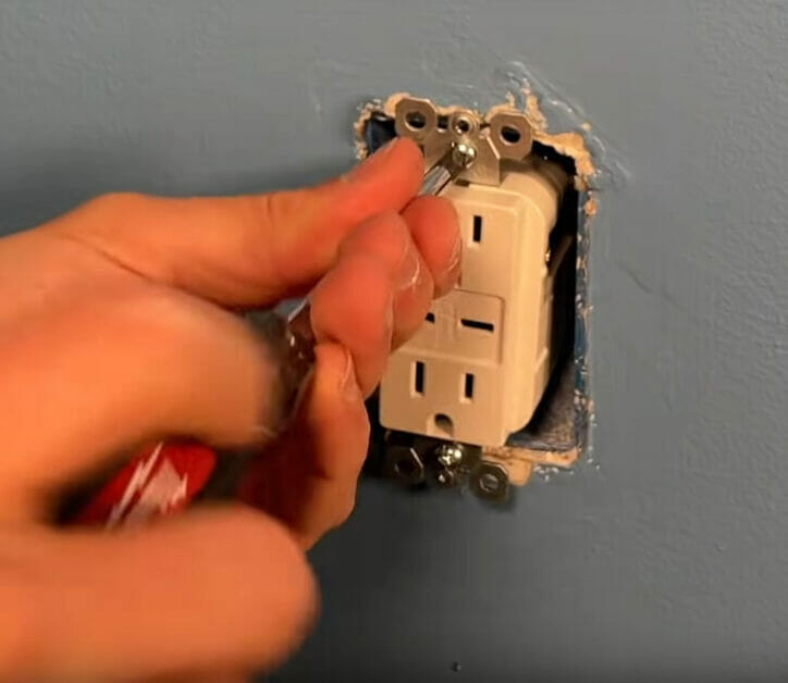 A person attaching the outlet using scewdriver