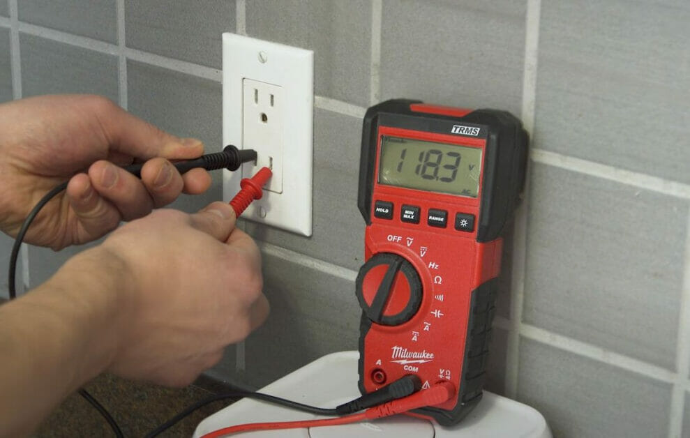 A person is measuring the voltage if there is power in the outlet
