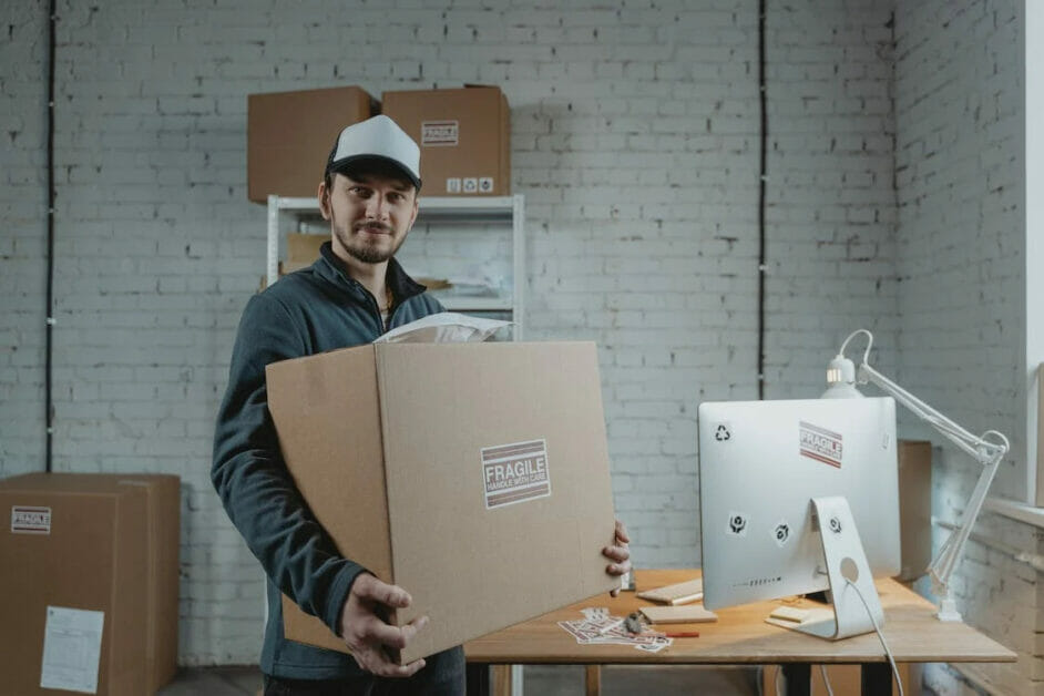 a delivery boy holding a box beside a computer desk