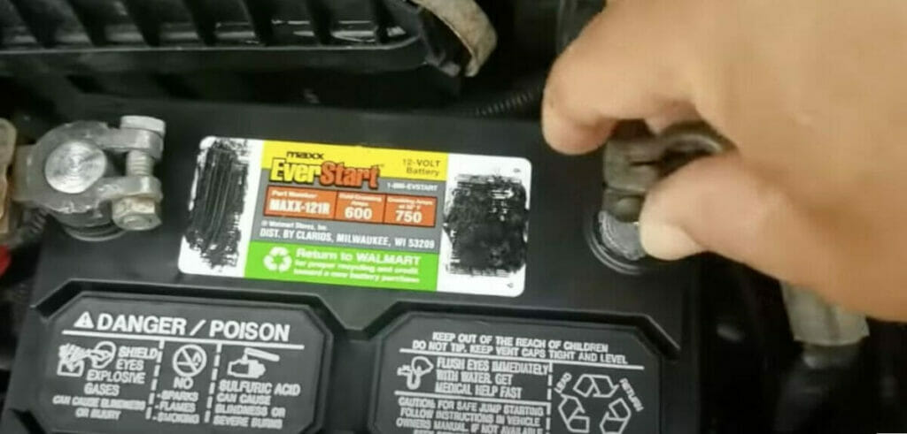 a hand disconnecting negative terminal on the car's battery