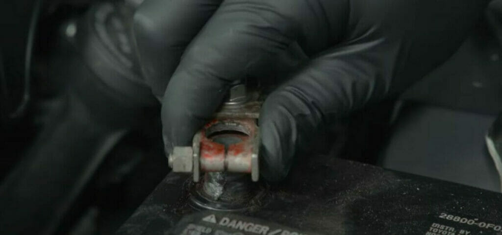 a hand disconnecting the battery from the negative terminal first