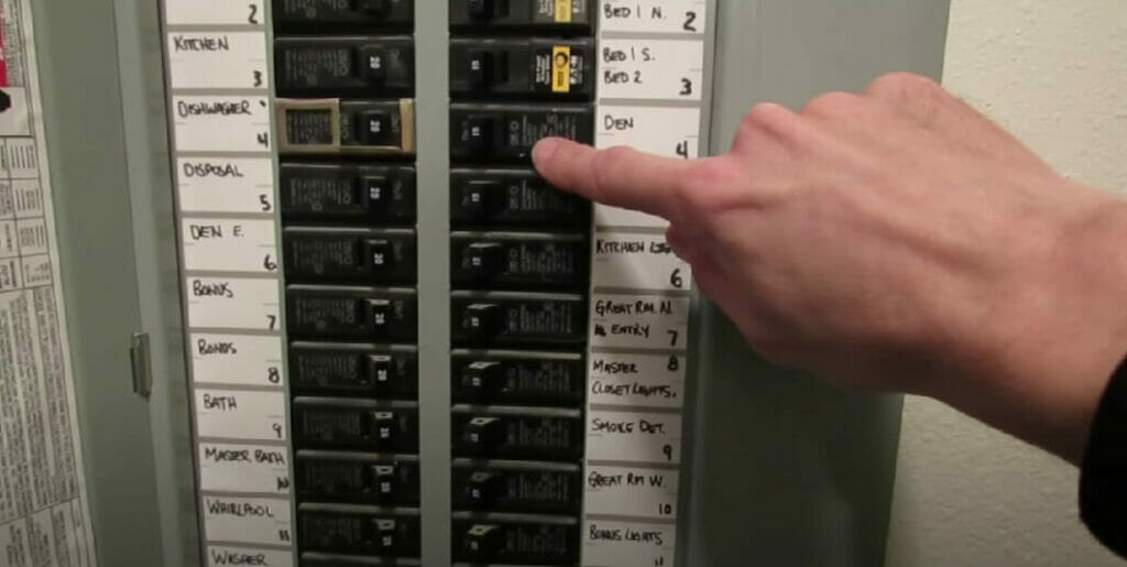 a man's hand turning off breaker on a main electrical panel