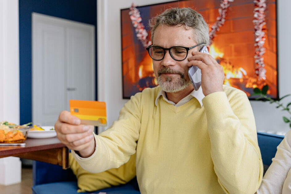 a senior citizen man on the phone holding a credit card