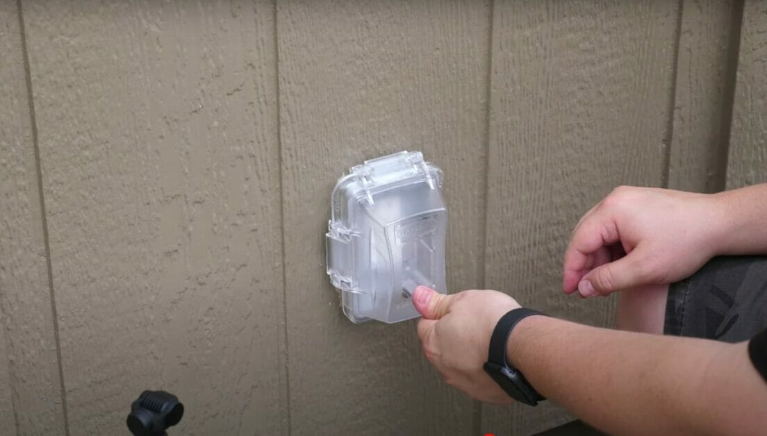 man checking an outdoor outlet with cover