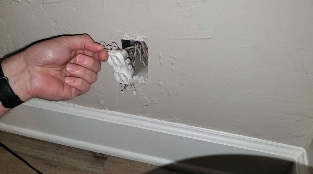 man checking on a faulty wall outlet