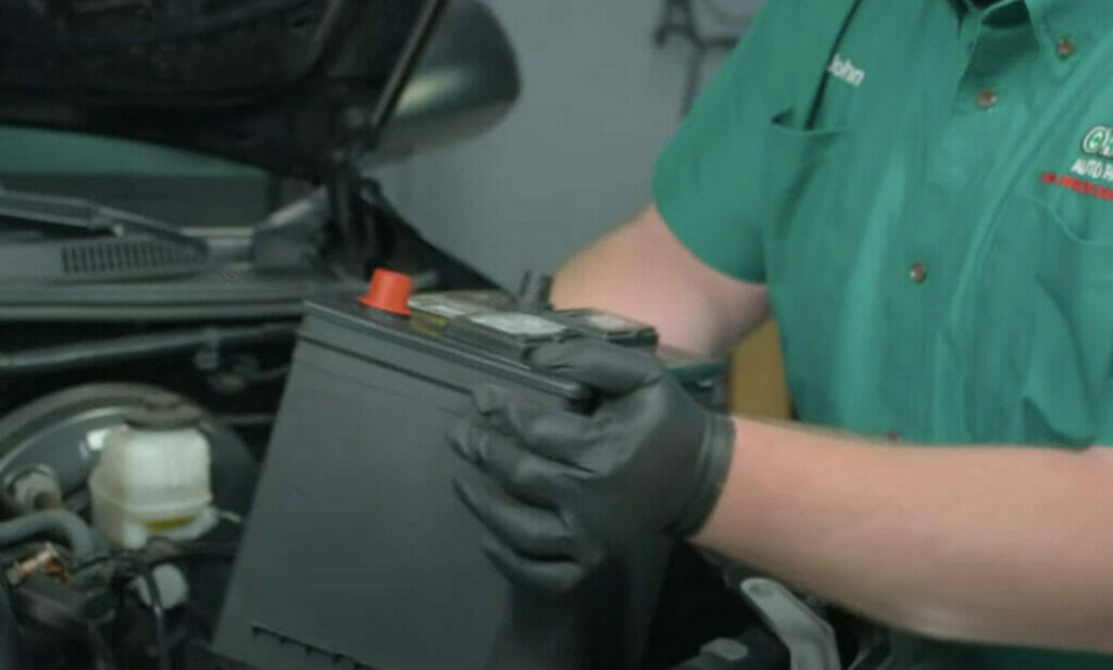 man replacing his car's old battery with a new one