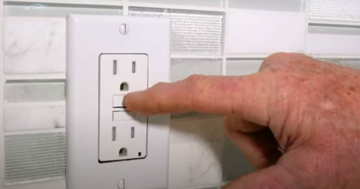 man trying to reset a GFCI outlet
