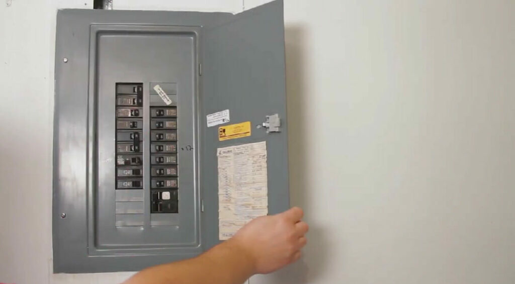man's hand opening the main electrical panel