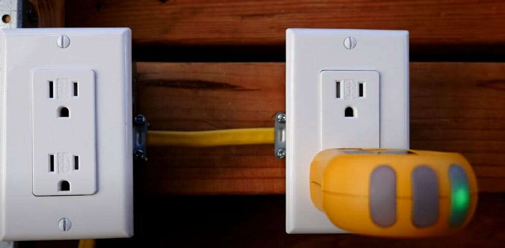 two outlets, one with outlet tester device on its prong