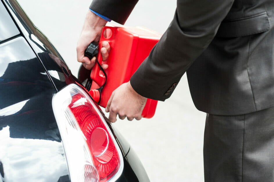 a man in a black suit refueling his car