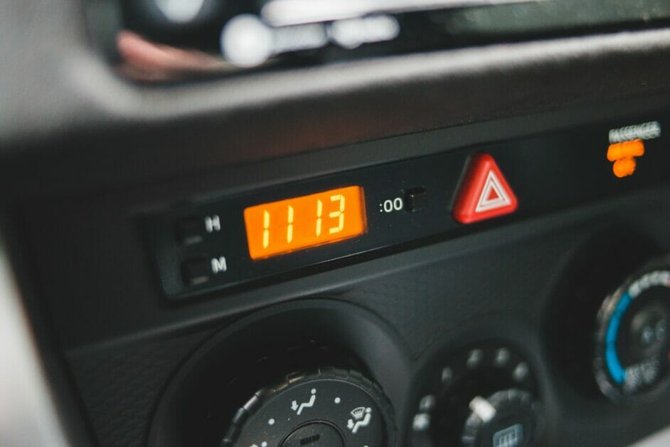 car's hazard button besides a digital clock
