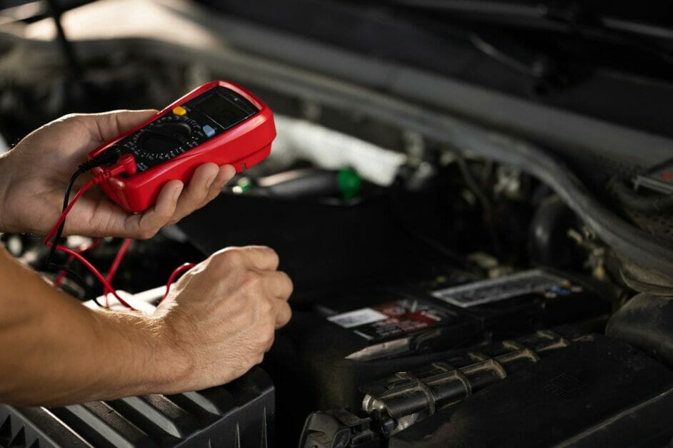 man using a multimeter to check his car's battery voltage