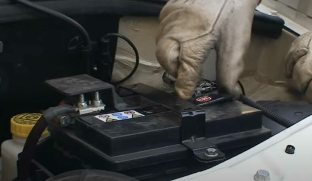 man with gloves checking the water level of his car battery