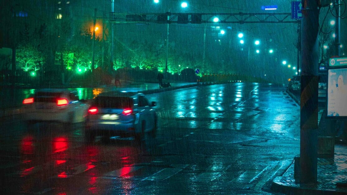 two cars driving on the street in a rainy night