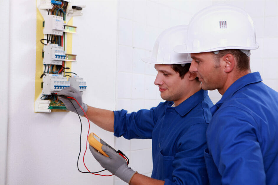 two electricians checking wires using multimeter