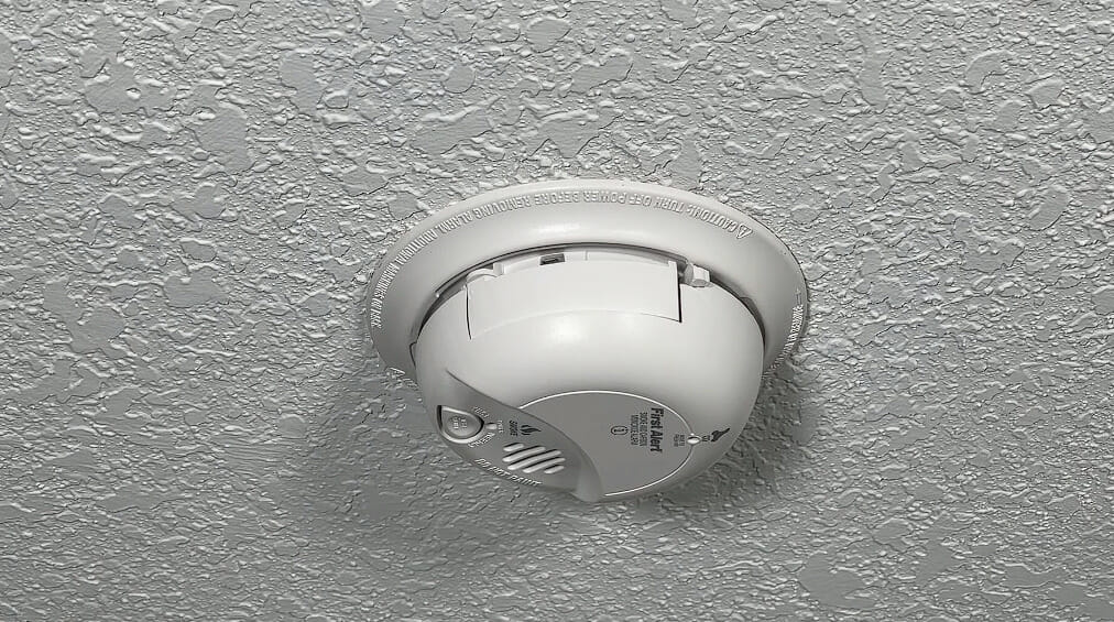 a white smoke detector in a white ceiling