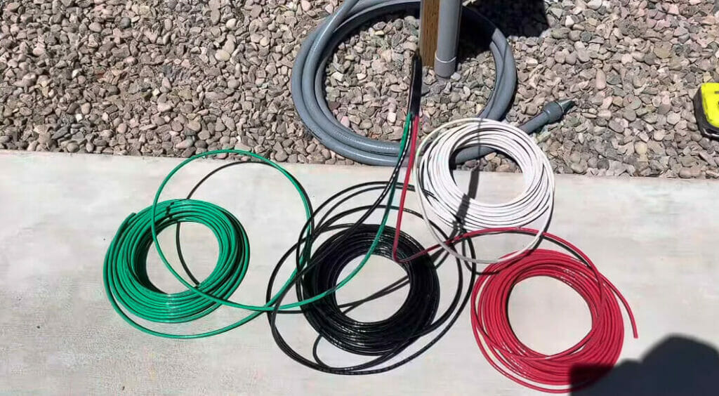 gray, green, black, white and red wires rolled and laid on the ground