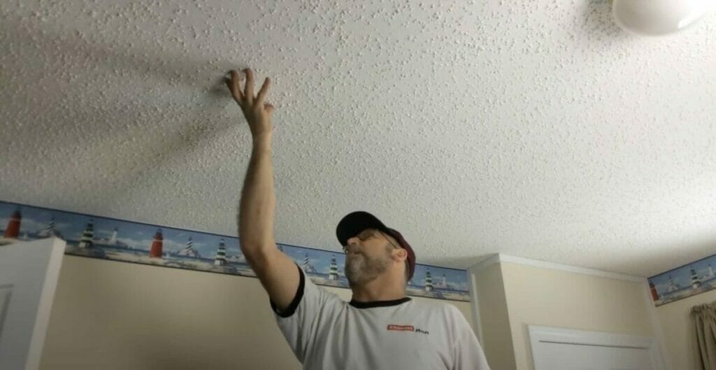 man choosing location on his home ceiling for smoke detector