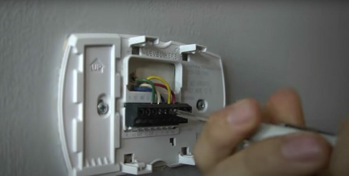 man screwing the back of the thermostat with wires