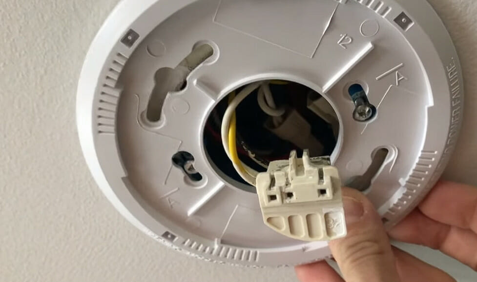 man showing the hard-wired side of a smoke detector