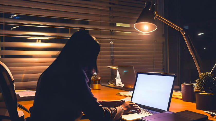woman working on her laptop at night with warm light