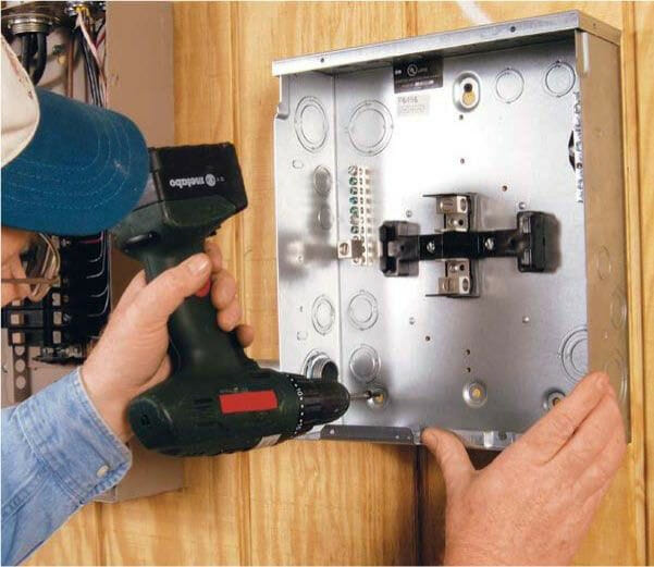 A man is using a screwdriver to install a circuit breaker box