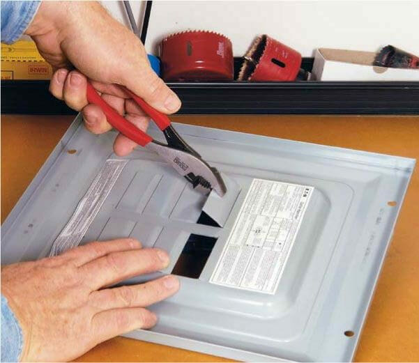 A person cutting a metal plate with pliers