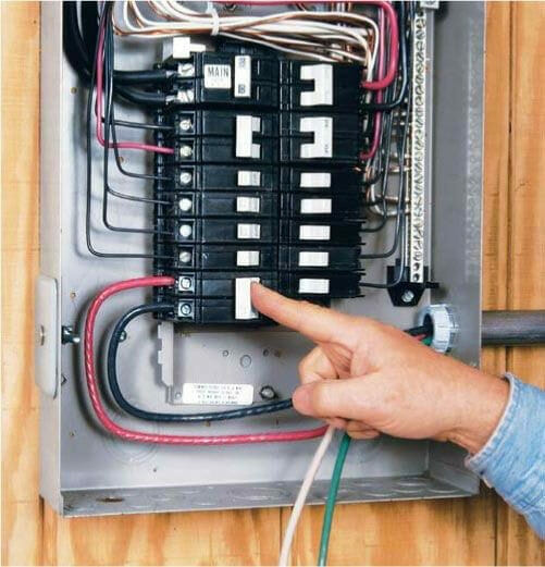 A person is pointing at an electrical panel