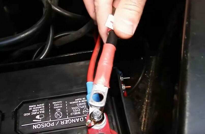 A person is using a wire to connect a battery to a car
