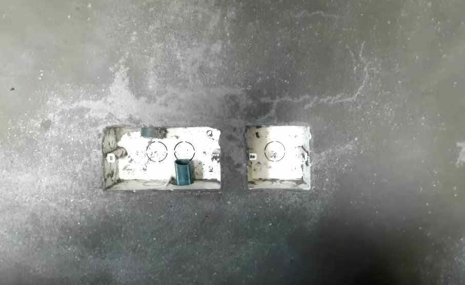 A picture of a light switch on a concrete floor, showcasing effective wire concealment techniques