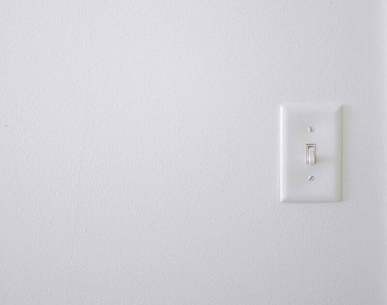a white single pole light switch on a white wall