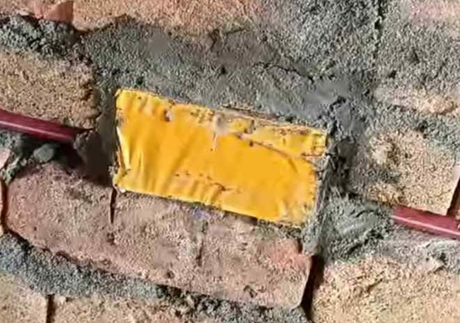A yellow cover cleverly concealing wires on a brick wall