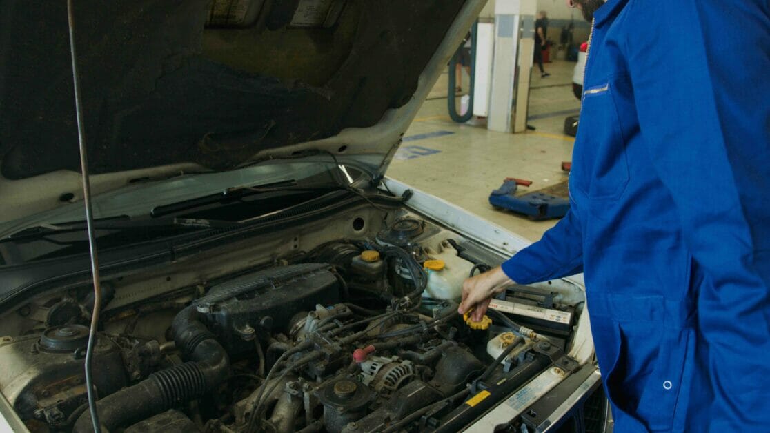 An automotive man in blue suit checking up the car hood